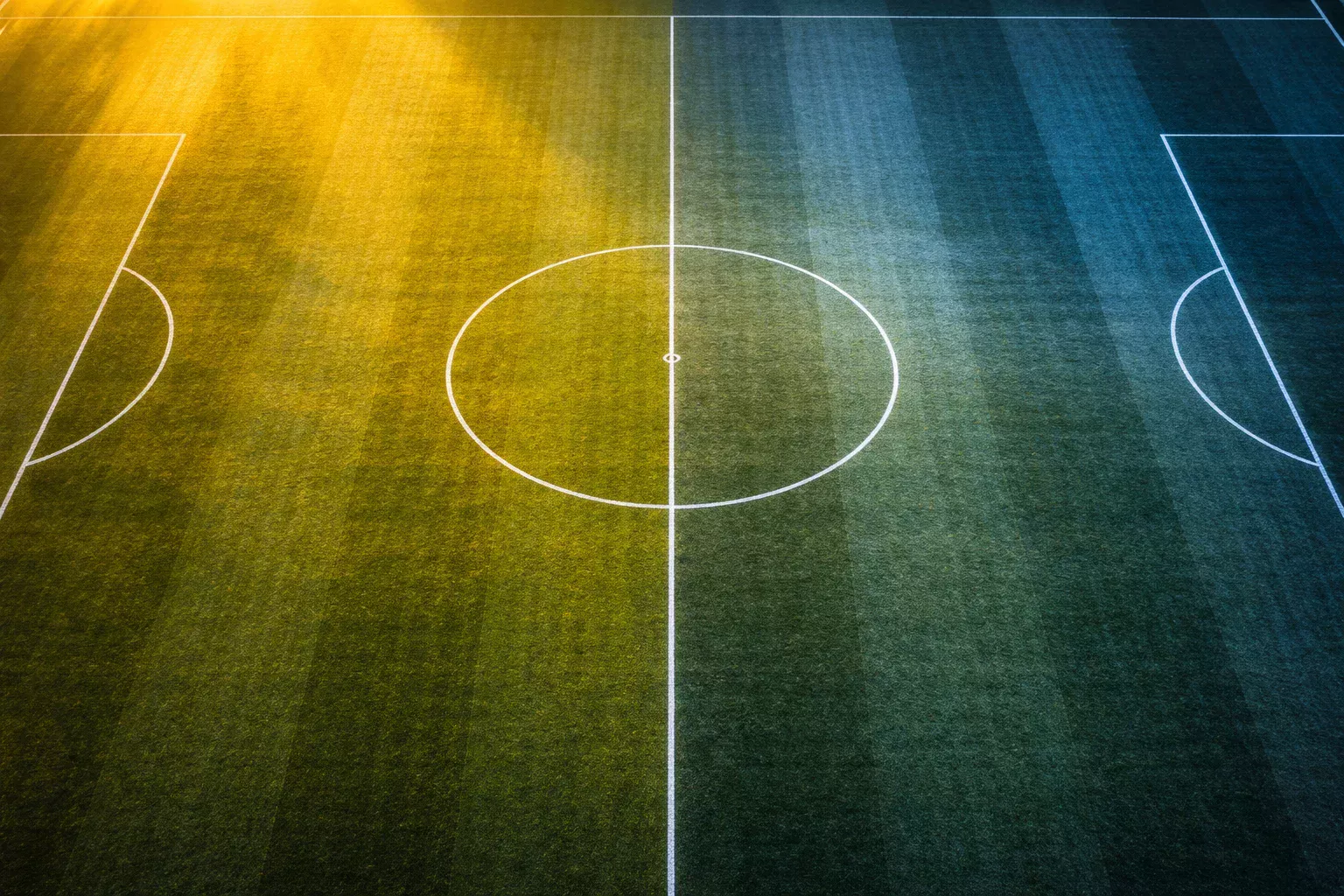 Due metà di un campo da calcio viste dall'alto con illuminazione diversa